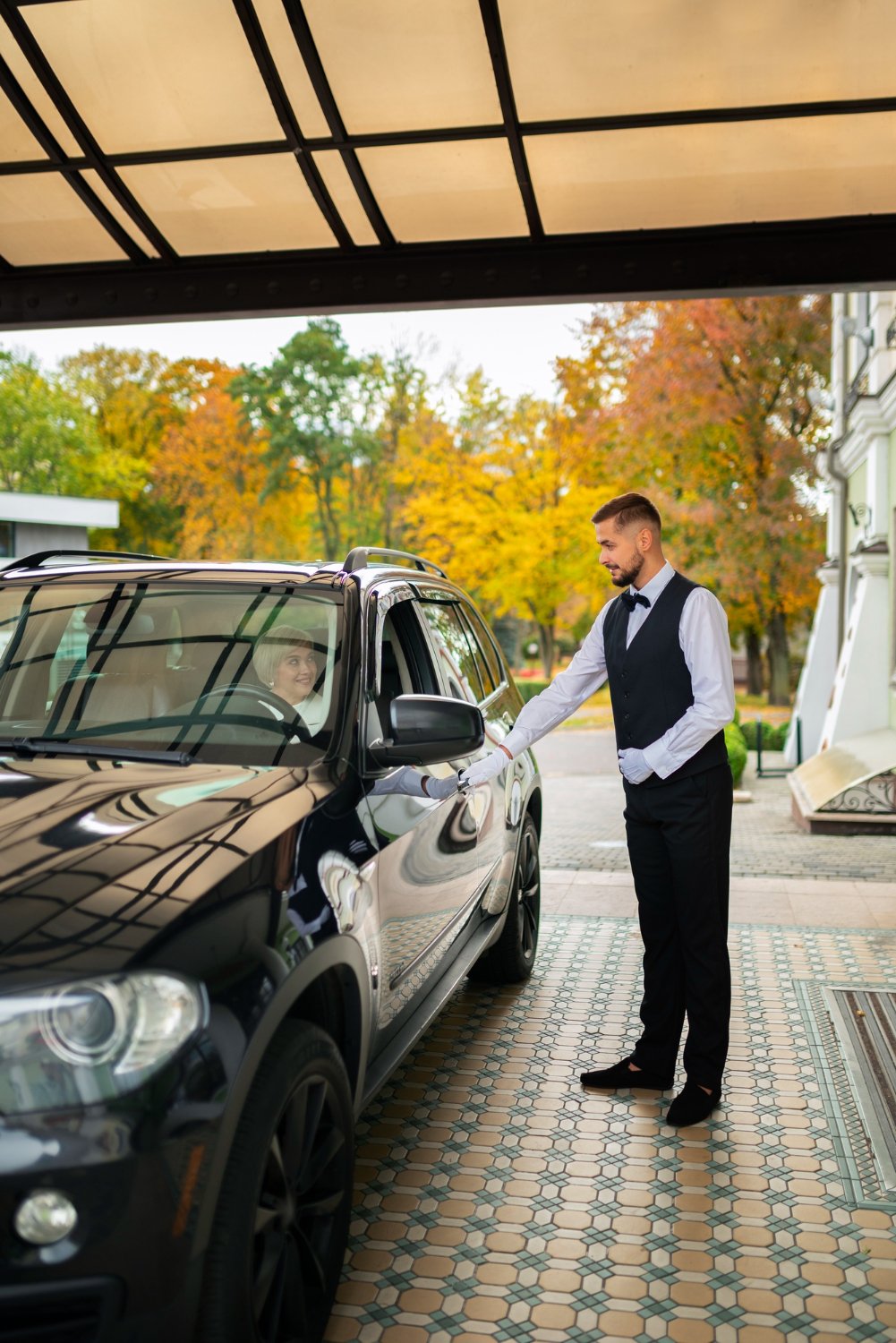 Professional valet attendant beside a luxury car